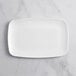 A white rectangular Visions plastic coupe platter on a marble surface.