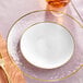 A Visions white plastic plate with gold rim on a table.