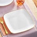 A Visions white square plastic plate with gold trim.