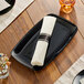 A black rectangular plastic coupe platter with a white napkin rolled up on it.
