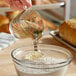 A person pouring Malt Products RiceRite Rice Syrup into a measuring cup