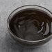 A bowl of CaneRite Organic Blackstrap Molasses in a bowl of liquid on a grey surface.