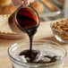 A person pouring Malt Products CaneRite Blackstrap Molasses into a bowl of flour.