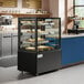 An Avantco black square dry bakery display case with food on it.