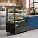 An Avantco black square dry bakery display case with trays of pastries.