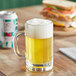 A glass of Untitled Art Italian Style Non-Alcoholic Pilsner next to a can of beer on a table.