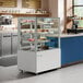 A white Avantco refrigerated bakery display case filled with cakes.