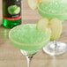 A green drink in a glass with DaVinci Gourmet Classic Green Apple Flavoring and a slice of green apple.