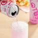 A hand pours Lotus Plant Power pink energy drink into a glass.