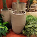 A group of Floridis Argos round beige planters with green plants in them.