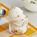 A glass bowl of Lloyd's of Pennsylvania Almond hard serve ice cream with a spoon.