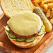 A burger with Violife Smoked Gouda cheese and pickles on a wooden surface.