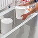 A man holding a white bucket filled with 2.5 gallon white HDPE ice cream tubs.