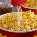 A bowl of popcorn with Sunglo White Popcorn Salt being poured over it.