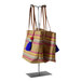 A group of striped tote bags with tassels on a double-sided adjustable-height countertop purse display rack.