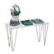 A white rectangular display table with a black and blue patterned cloth and a mannequin wearing a green and black sports garment.