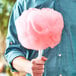 A man holding a white stick with pink cotton candy.