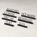 A group of black stainless steel laser-cut tabletop signs with "Oat" print on a counter.