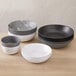A stack of matte black American Metalcraft melamine bowls on a table.