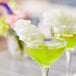 A close-up of a glass of green liquid with cotton candy on top.
