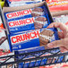 A hand holding a package of CRUNCH chocolate bars.