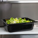 A black Vollrath plastic food pan filled with lettuce on a counter.