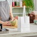 A woman standing at a counter with a white Choice paper bag.