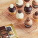 A tray of cupcakes with white and chocolate frosting and chocolate balls on top on a table next to a Ferrero Collection candy variety pack.