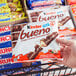 A hand holding a package of KINDER Bueno chocolate bars with a bite taken out of one.