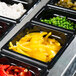 A black Vollrath Super Pan with yellow food in it on a counter.