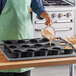 A woman pouring a mixture into a Sasa Demarle jumbo muffin mold.