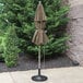 A taupe Grosfillex umbrella on an aluminum pole over a patio table.