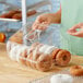 A woman using a Polar Pak clear plastic hinged container to store doughnuts.