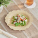 A Bambu Veneerware bamboo plate with salad on a table.