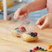 A person holding a Polar Pak clear plastic 2-compartment tart container with food in it.