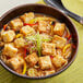 A bowl of soup with tofu and vegetables.