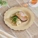 A Bambu Veneerware bamboo plate with meat and vegetables on it on a table.