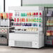 An Avantco white vertical open air merchandiser with drinks on shelves.