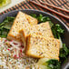 A bowl of rice, Nasoya Super Firm Tofu, and greens with chopsticks.