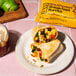 A plate with Eat Just Egg Southwest Breakfast Burritos and lime wedges next to a drink.