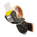 A gloved hand using an Encore Packaging mousetrap-style tape dispenser to hold clear tape.