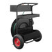 A black metal cart with a red wheel and a green hose.