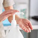 A person using a Lavex plastic pump dispenser on a white bottle.