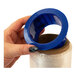 A hand using blue plastic ring to hold clear plastic film on a roll.