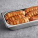 A metal tray of Ditsch Authentic German Soft Pretzel Sticks with salt packets on a table.