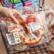 A hand holding a plastic bag of Ditsch soft pretzels