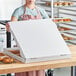 A woman holding a white Choice bakery box full of food.