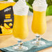 Two glasses of DaVinci Gourmet Mango Mania smoothie with whipped cream on top.