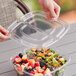 A hand opening a Sabert clear plastic container with salad inside.