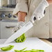 A person using a Choice Classic Bolster Chef Knife to cut a green bell pepper.